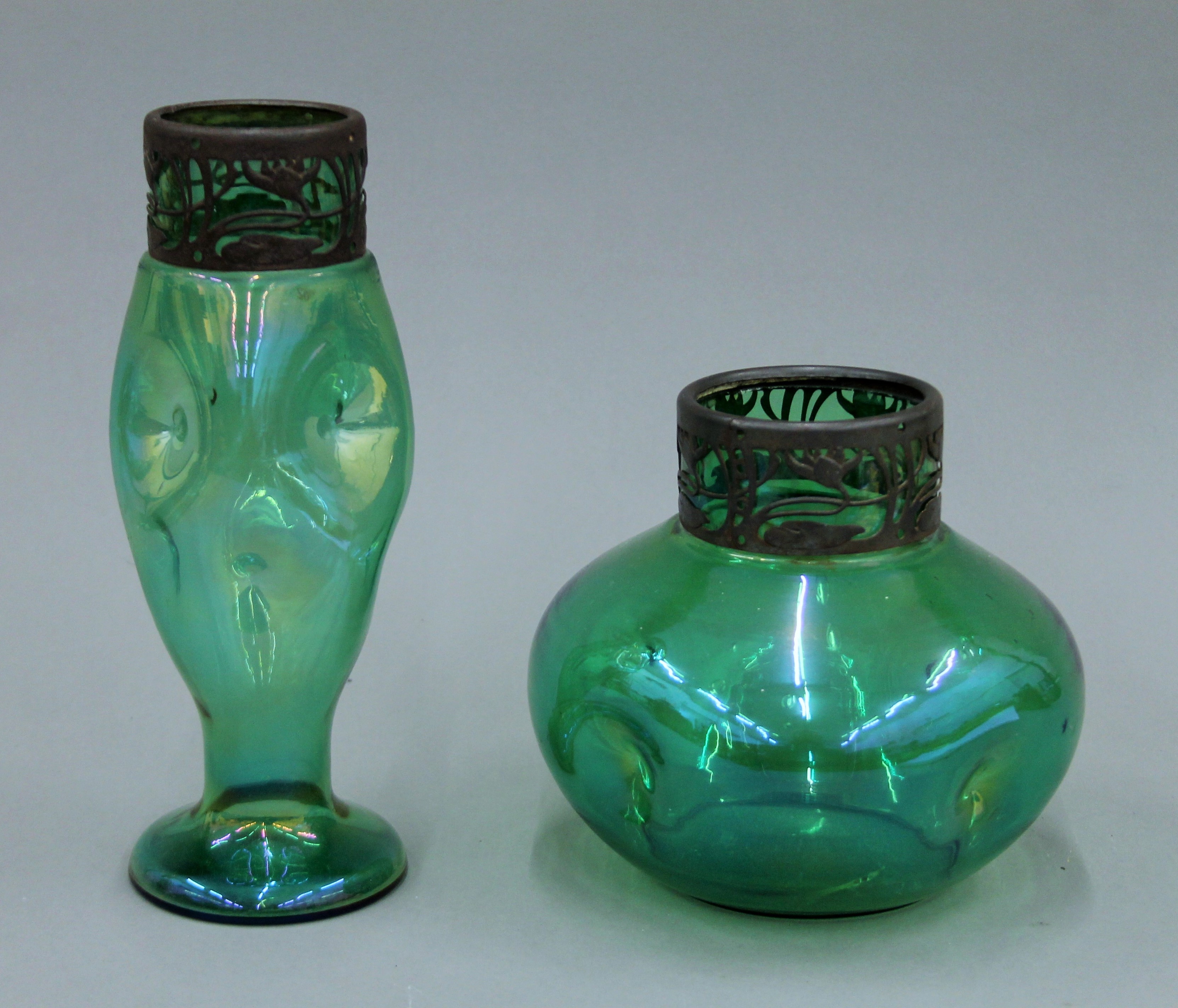Two metal rimmed Art Nouveau green glass vases. The largest 24 cm high.
