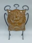 An Arts and Crafts wrought iron and copper fire screen, with embossed panel, unsigned. 78 cm high.