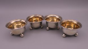 Four Victorian circular silver salt cellars, each on three ball feet and gilded interiors,