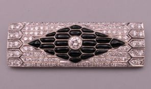 An Art Deco style unmarked white gold or platinum diamond and onyx brooch. 4.25 cm long. 9.