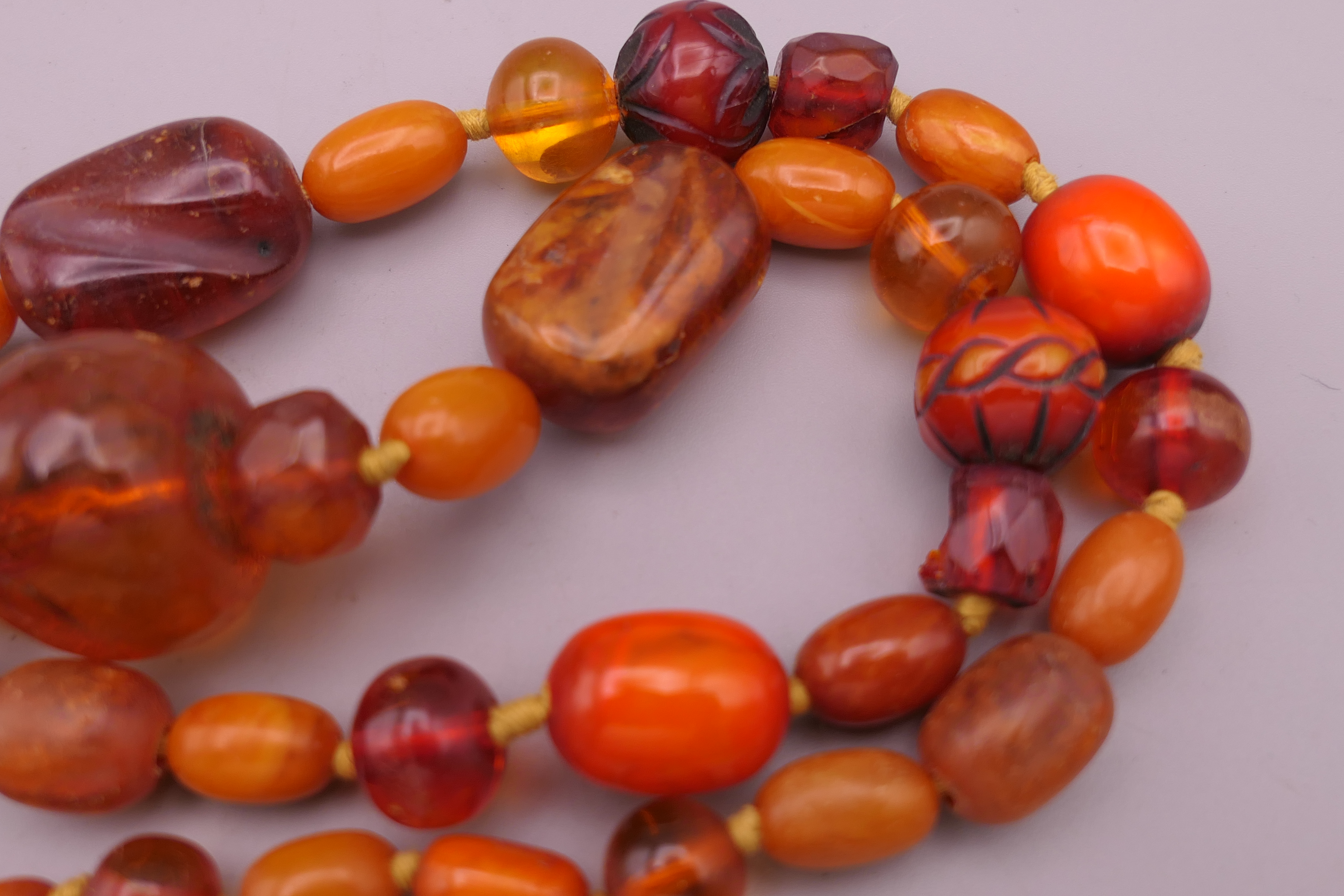 An amber bead necklace including two carved beads. 77 cm long. - Image 2 of 4