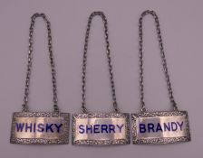 Three enamel and silver decanter labels. 5 cm wide.