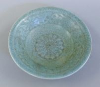 A Chinese celadon dish decorated with calligraphy. 14 cm diameter.