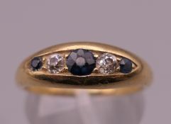An early 20th century 18 ct gold graduated five stone sapphire and diamond half hoop ring.