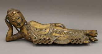 A Burmese carved wood and gilded reclining Buddha with mirrored glass inlay. 57 cm long.