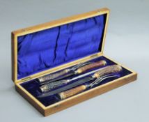 A cased set of horn handled carving knives and forks. The case 43 cm wide.