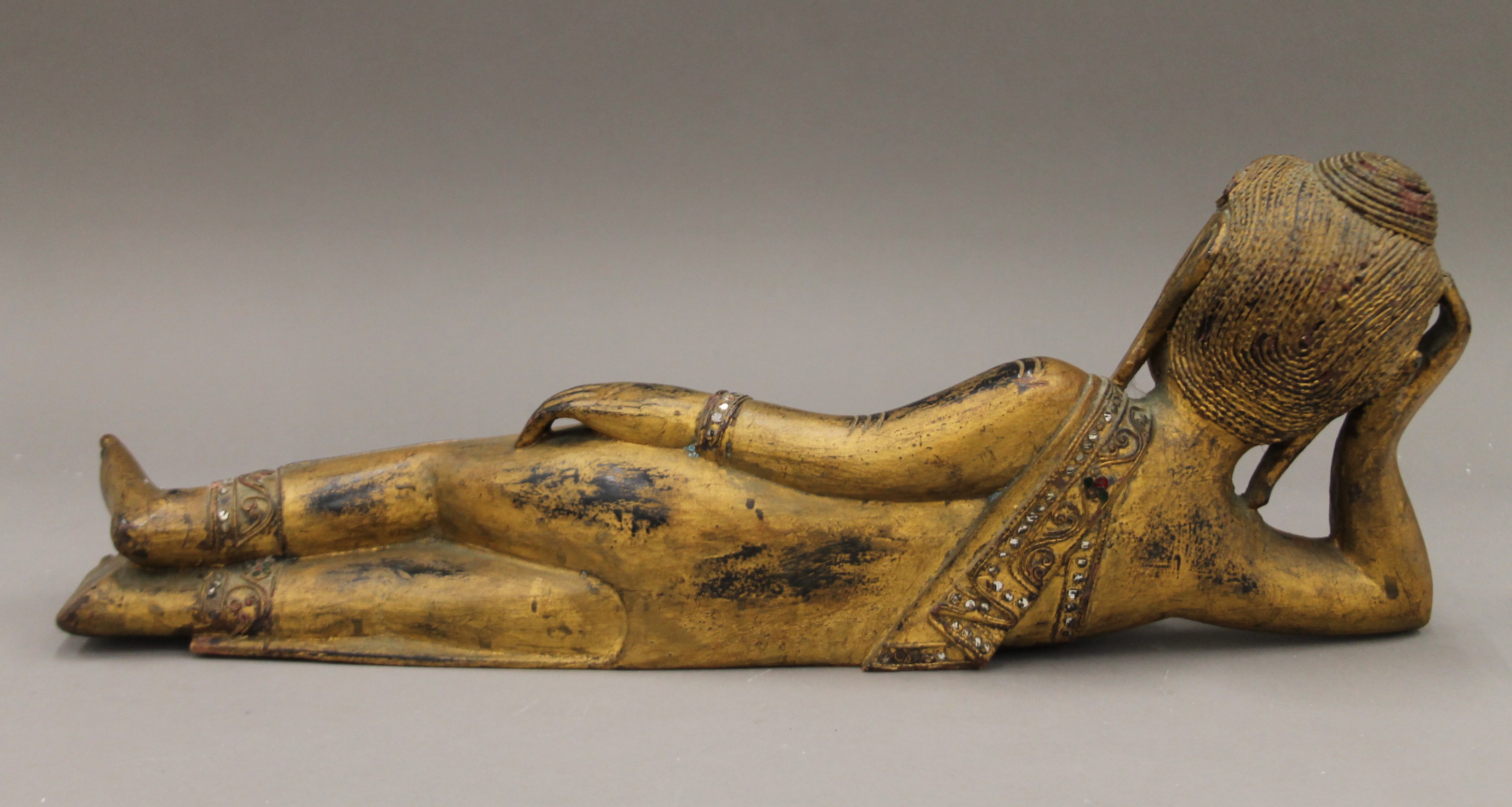 A Burmese carved wood and gilded reclining Buddha with mirrored glass inlay. 57 cm long. - Image 4 of 4