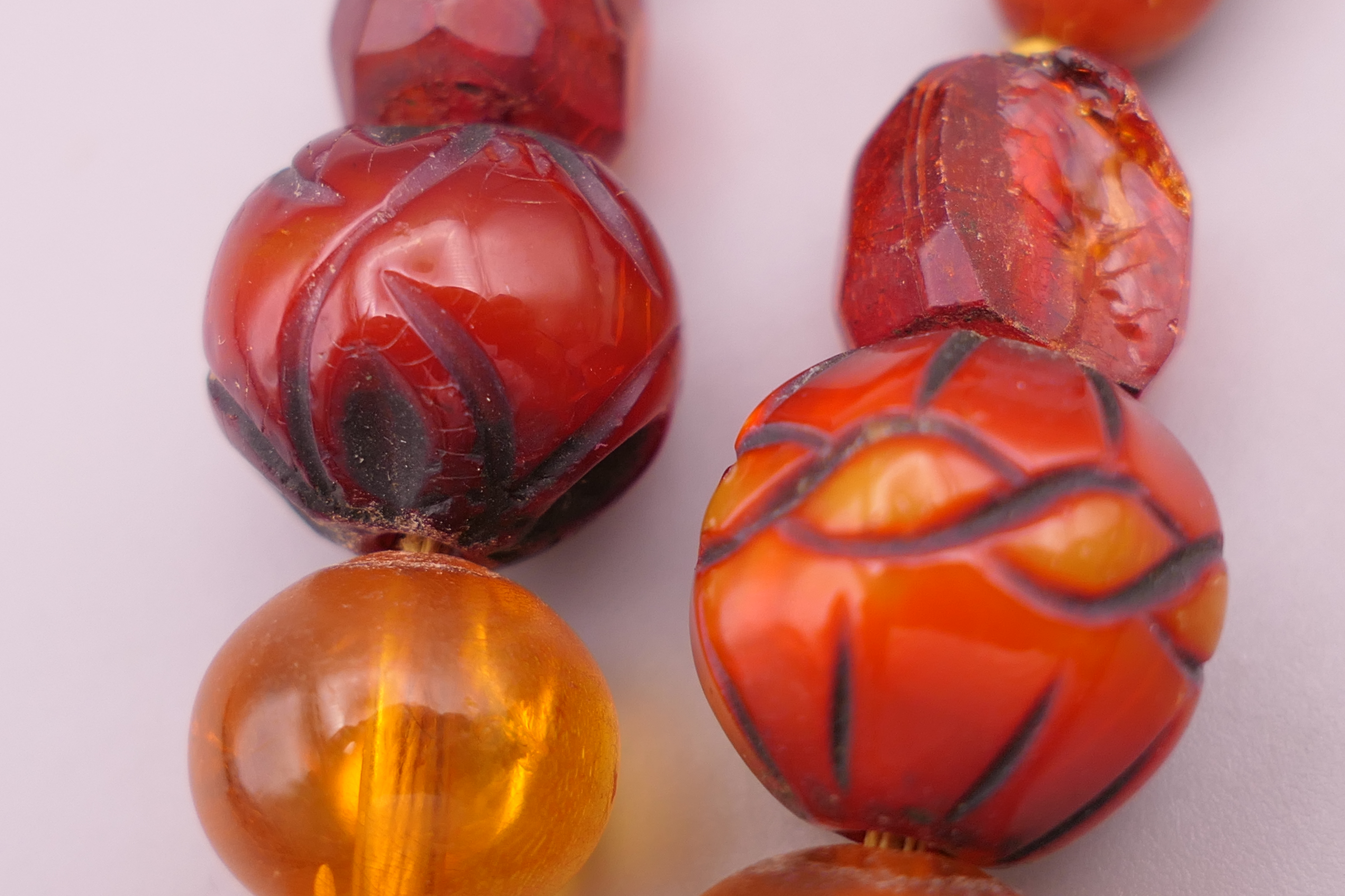 An amber bead necklace including two carved beads. 77 cm long. - Image 4 of 4