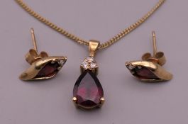 A 9 ct gold garnet and diamond pendant on chain and a pair of matching earrings. The pendant 1.