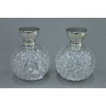 A pair of cut glass and silver topped vintage scent bottles, hallmarks rubbed. 11 cm high.