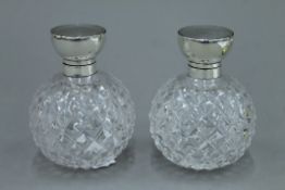 A pair of cut glass and silver topped vintage scent bottles, hallmarks rubbed. 11 cm high.