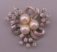 An 18 ct white gold diamond and pearl brooch. 3 cm wide. 6.7 grammes total weight.