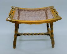 An early 20th century stool with string woven seat supported on turned legs. 54.5 cm wide.