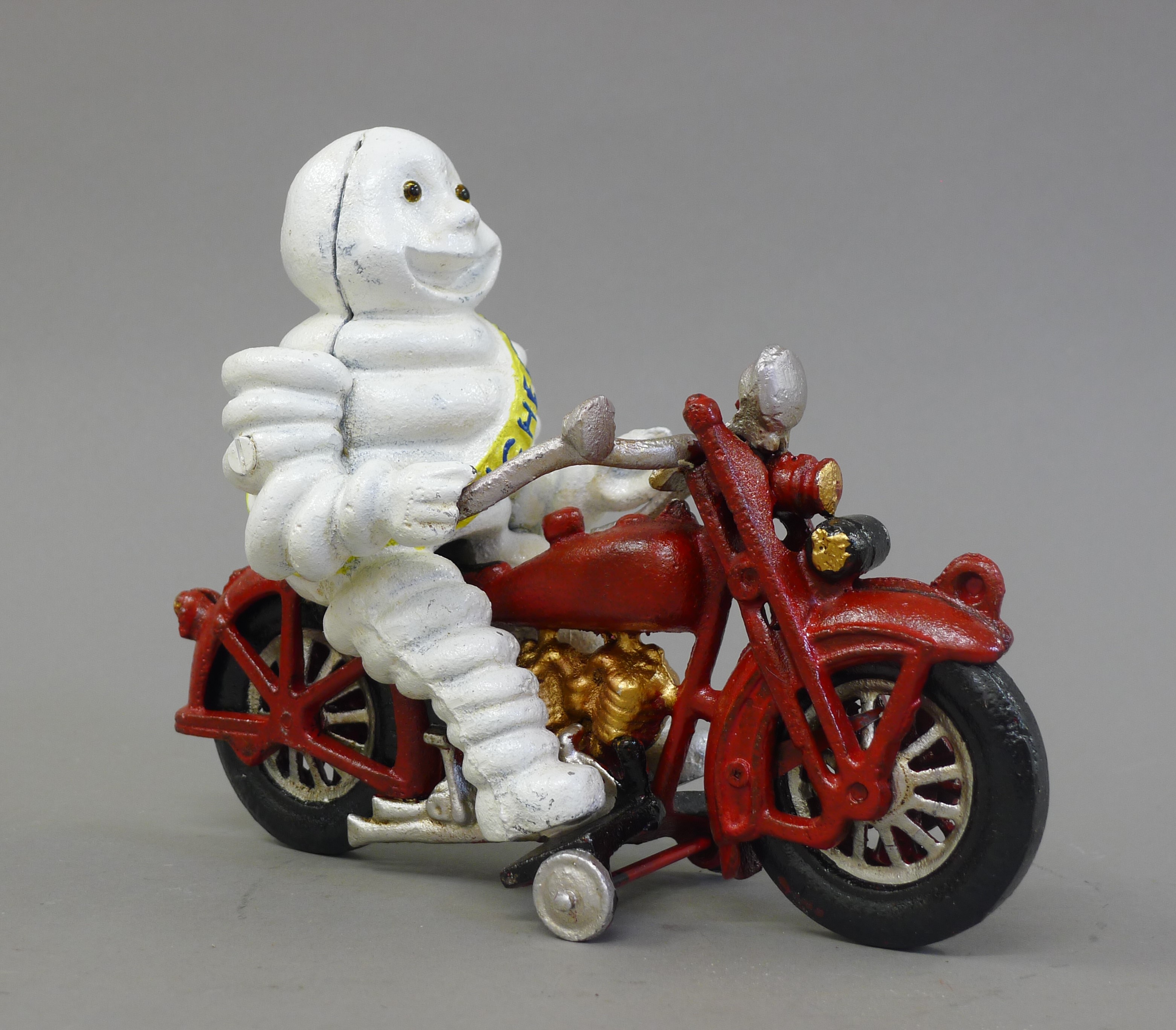 A cast iron model of a Michelin man on a motorcycle. 22 cm long.