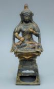 A bronze figure of a seated deity decorated with calligraphy. 24 cm high.