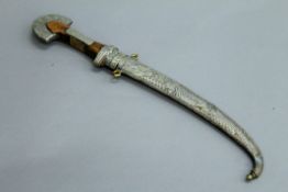A 19th century Middle Eastern steel bladed dagger (Kinjal), wood hilt and white metal sheaf.