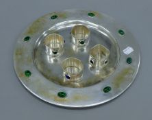 An Arts and Crafts white metal dish and four napkin rings. The former 30 cm diameter.