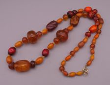 An amber bead necklace including two carved beads. 77 cm long.