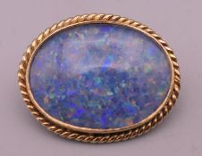 A late 20th century 9 ct gold opal doublet brooch, with rope twist surround. 2.5 cm wide. 4.