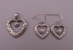 A silver heart shaped pendant and matching earrings. The former 3 cm high.