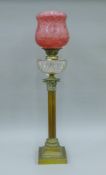 A Victorian brass Corinthian column oil lamp, with cut glass font and etched cranberry glass shade.
