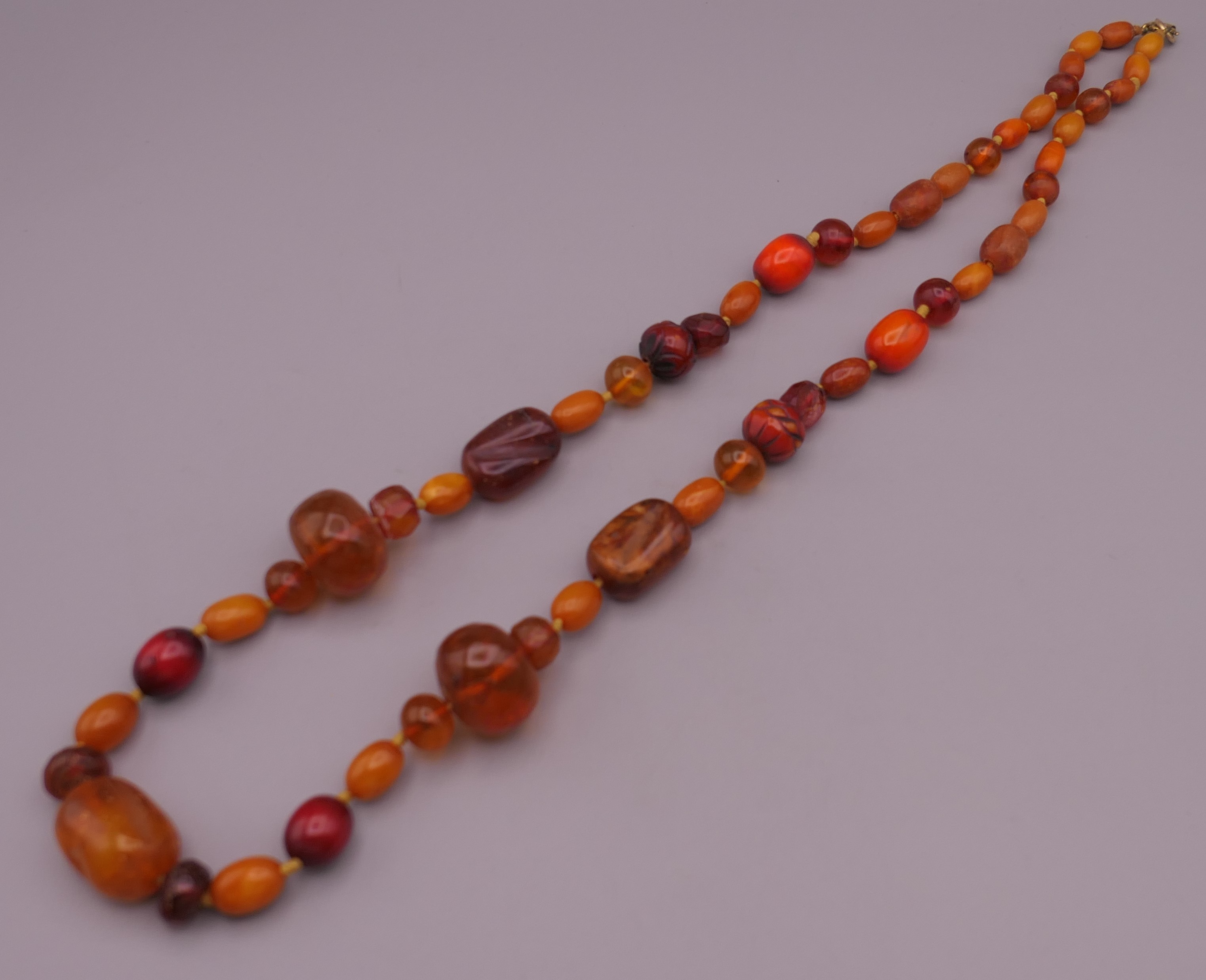 An amber bead necklace including two carved beads. 77 cm long. - Image 3 of 4