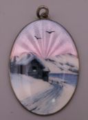 A silver and enamel pendant depicting a Scandinavian cottage in snow at sunset. 4.25 cm high.