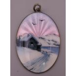 A silver and enamel pendant depicting a Scandinavian cottage in snow at sunset. 4.25 cm high.