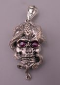 A silver skull and snake form pendant. 5.5 cm high.