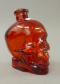 A red glass decanter formed as a skull. 16 cm high.