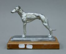 A spelter figure of a greyhound, on a wooden plinth base. 21.5 cm long.