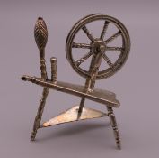 A miniature silver model of a spinning wheel. 6 cm high.