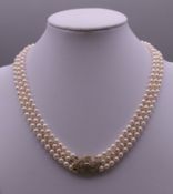 A triple string of cultured pearls with a 14 ct gold diamond clasp. 39 cm long.