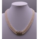 A triple string of cultured pearls with a 14 ct gold diamond clasp. 39 cm long.