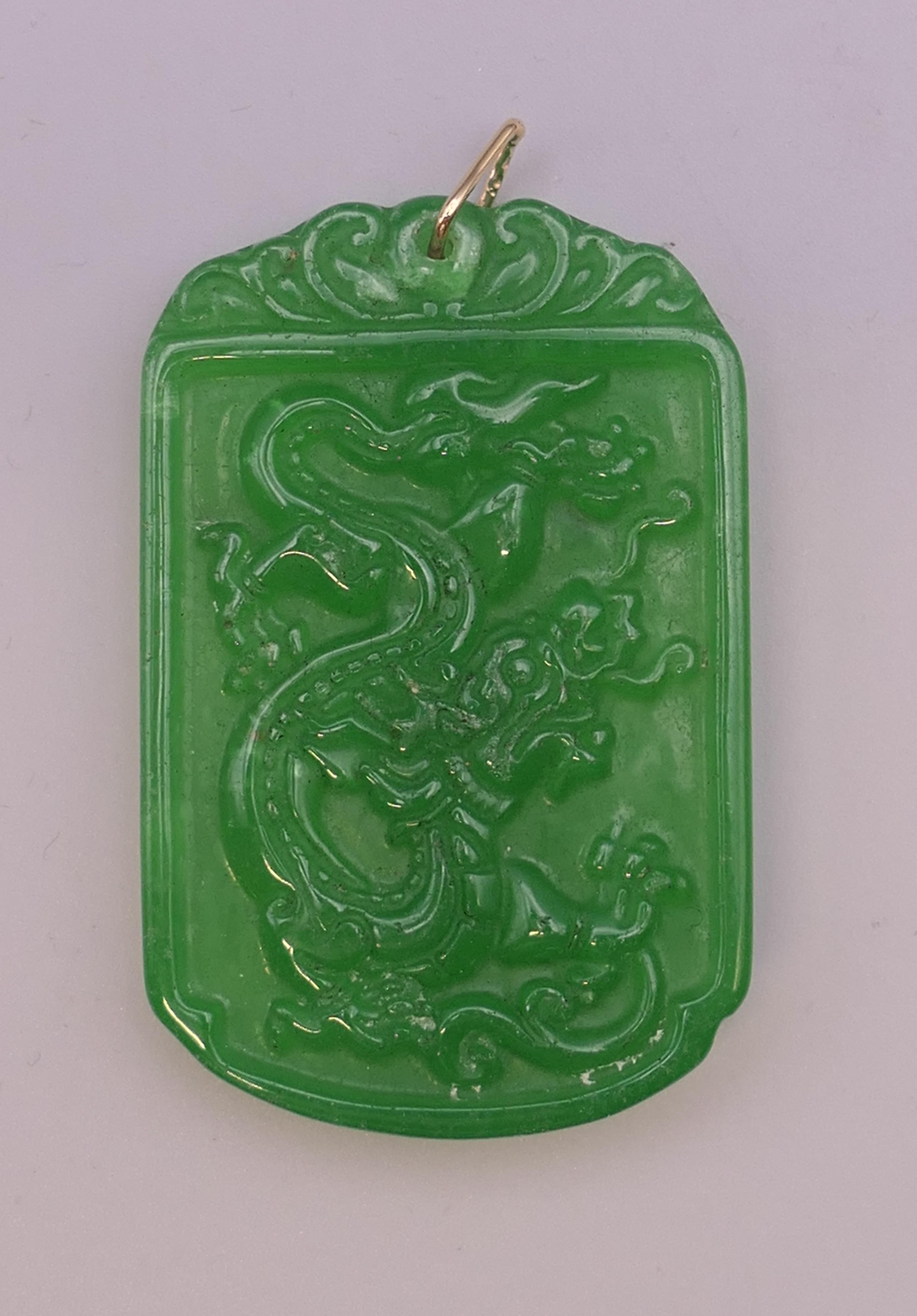 A gold mounted apple green jade pendant. 6 cm high.