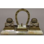 An onyx and brass desk stand, the inkwells with jockey's cap lids. 26 cm wide.