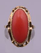 An unmarked gold coral set ring. Ring size O/P. 4.3 grammes total weight.