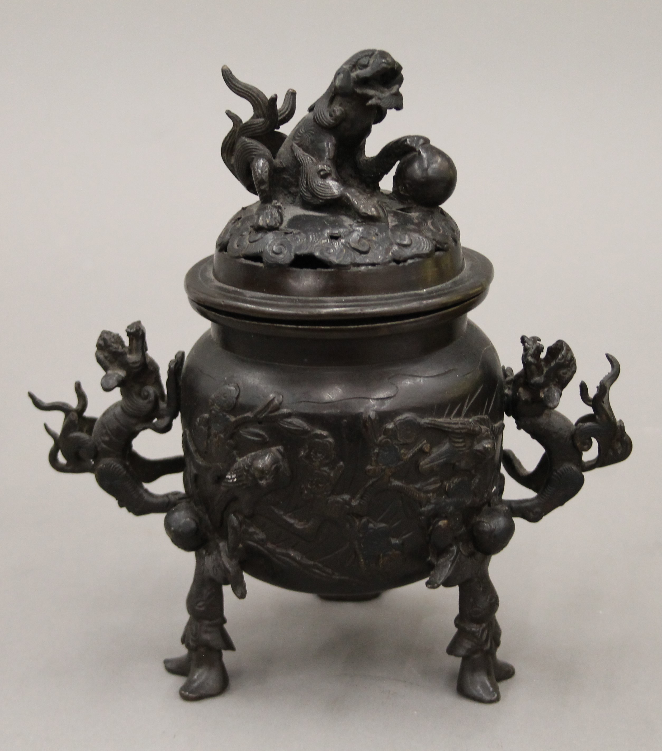 A Japanese patinated bronze tripod incense burner with dragon handles and pierced lid. 20 cm high.