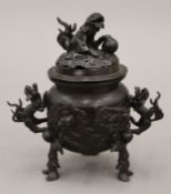 A Japanese patinated bronze tripod incense burner with dragon handles and pierced lid. 20 cm high.