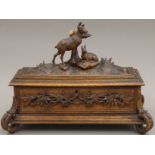 A Blackforest table casket with silk button interior, carved with two deer and foliage. 39 cm long.