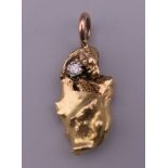 An unmarked gold (probably 18 ct) nugget pendant set with a diamond, on a 9 ct gold suspension loop.