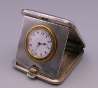 A silver cased travelling clock. 5 cm wide.