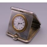 A silver cased travelling clock. 5 cm wide.