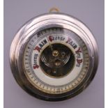 A silver cased aneroid barometer. 13.5 cm diameter.