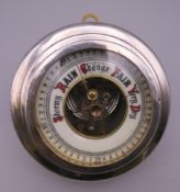 A silver cased aneroid barometer. 13.5 cm diameter.