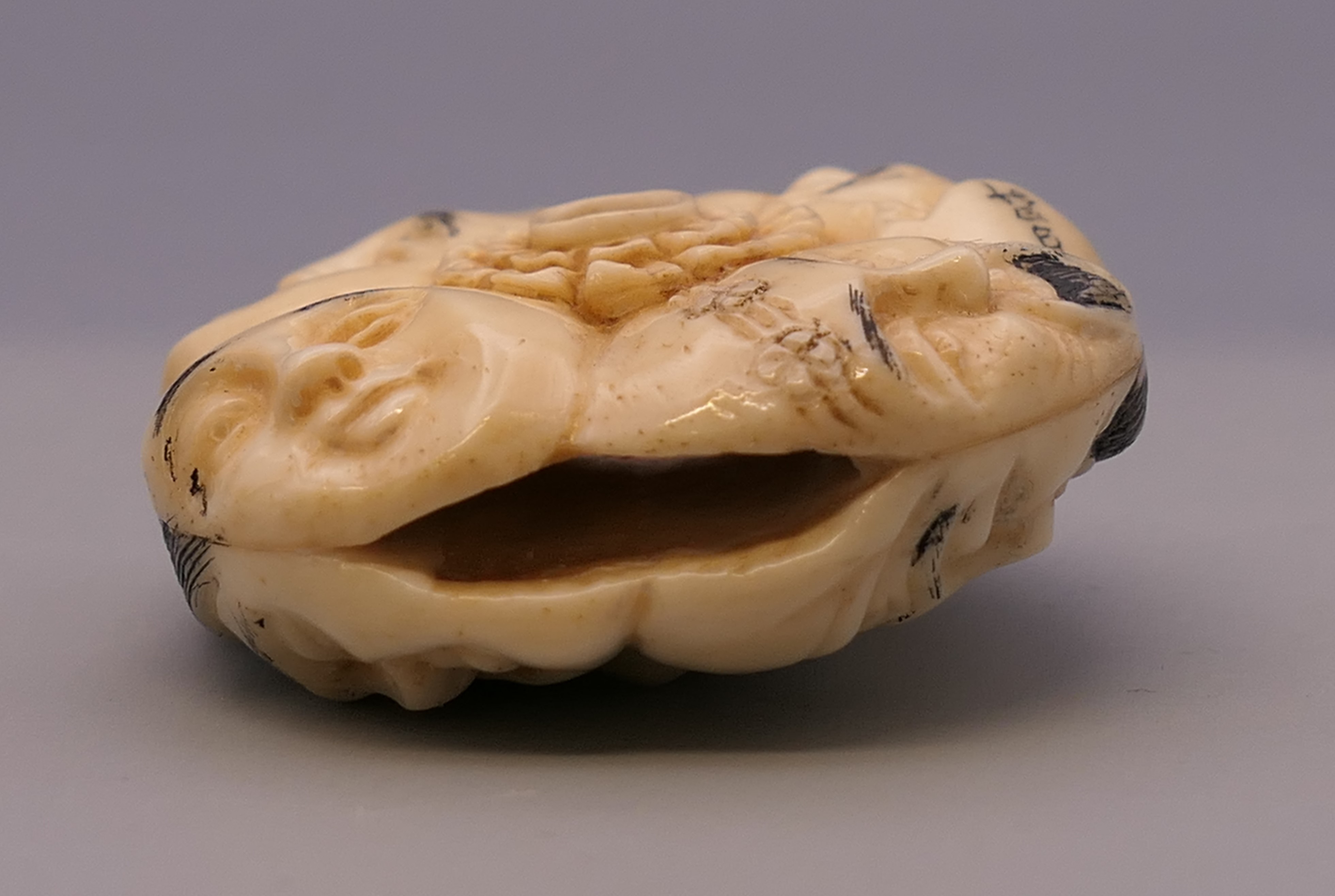 A bone toggle carved with faces. 4 cm diameter. - Image 5 of 5