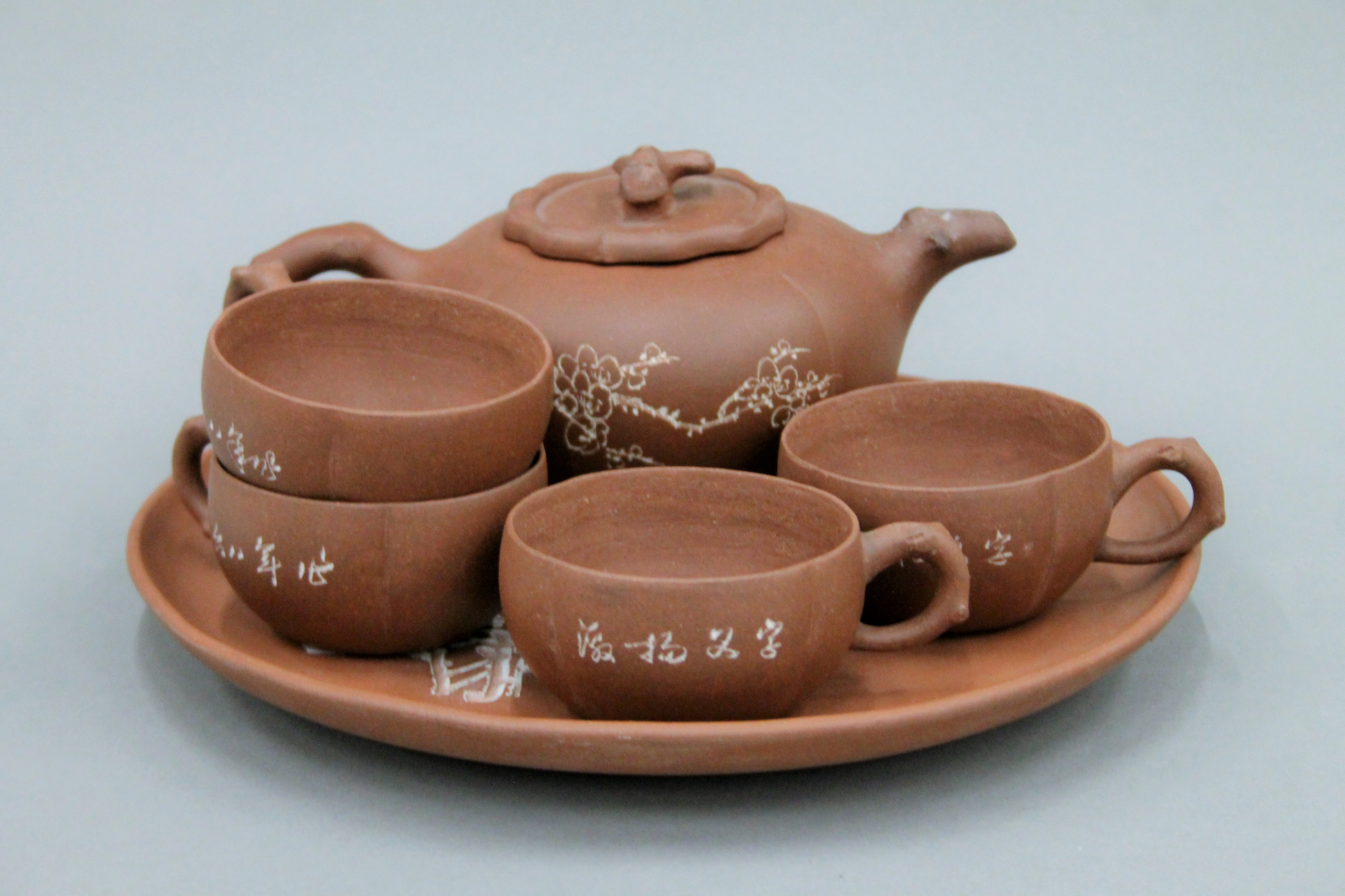 A Y-Hsing tea set comprising: a teapot, four cups and a tray, all with incised decoration.