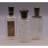 Three silver topped perfume bottles. The largest 8.5 cm high.