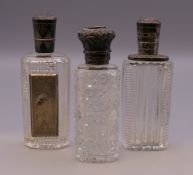 Three silver topped perfume bottles. The largest 8.5 cm high.