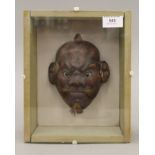 A Japanese lacquered Noh mask, with beaded eyes housed in a glazed display case. The case 25.